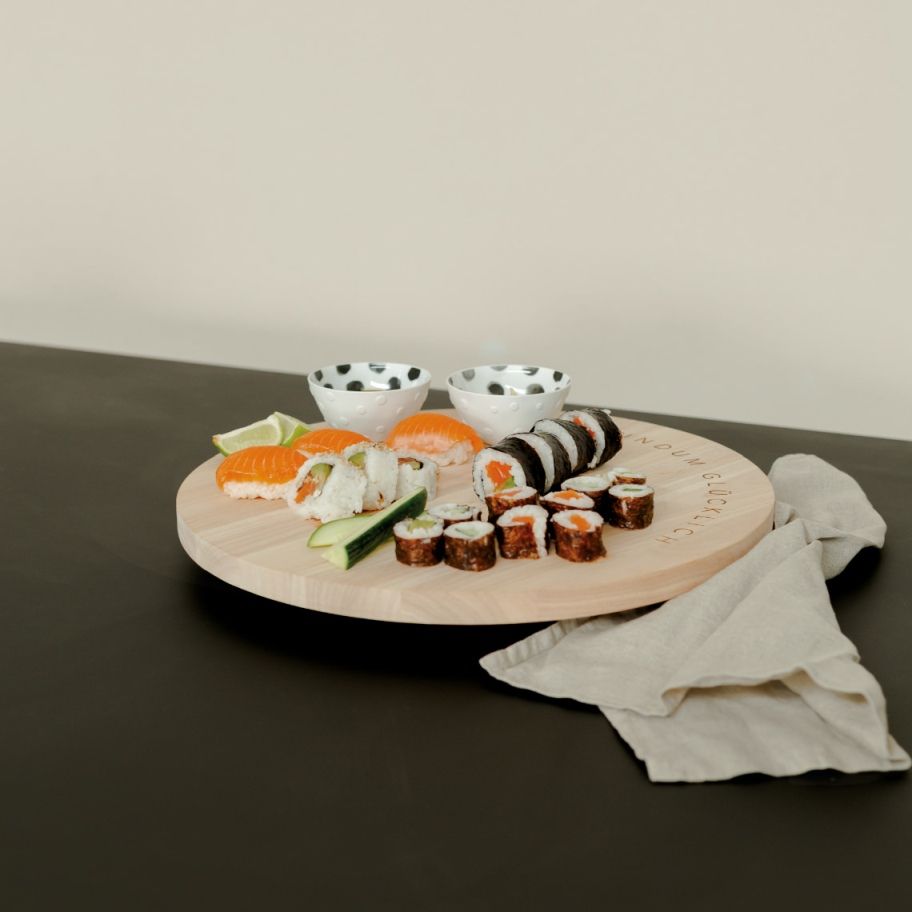 Drehplatte "Rundum Glücklich" mit Sushi-Arrangement: Maki, Nigiri, Sojaschalen und Limetten auf einer Holz-Servierplatte.