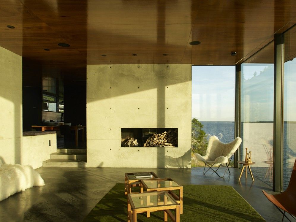 Heller Raum mit Iceland Mariposa Sessel aus Schaffell in Grau, Kamin und Seeblick.