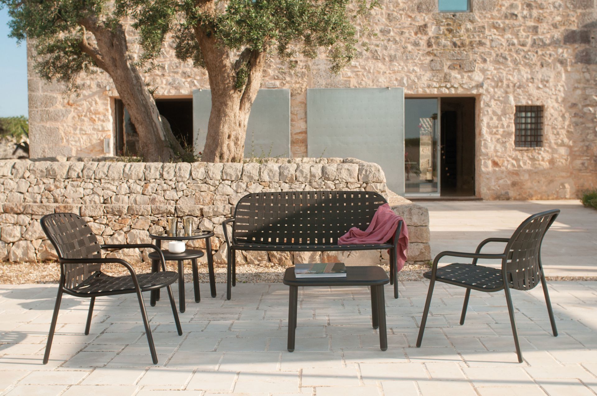 Emu Yard Lounge Chair Sessel und Gartenmöbel Set aus schwarzem Stahl vor Steinhaus.