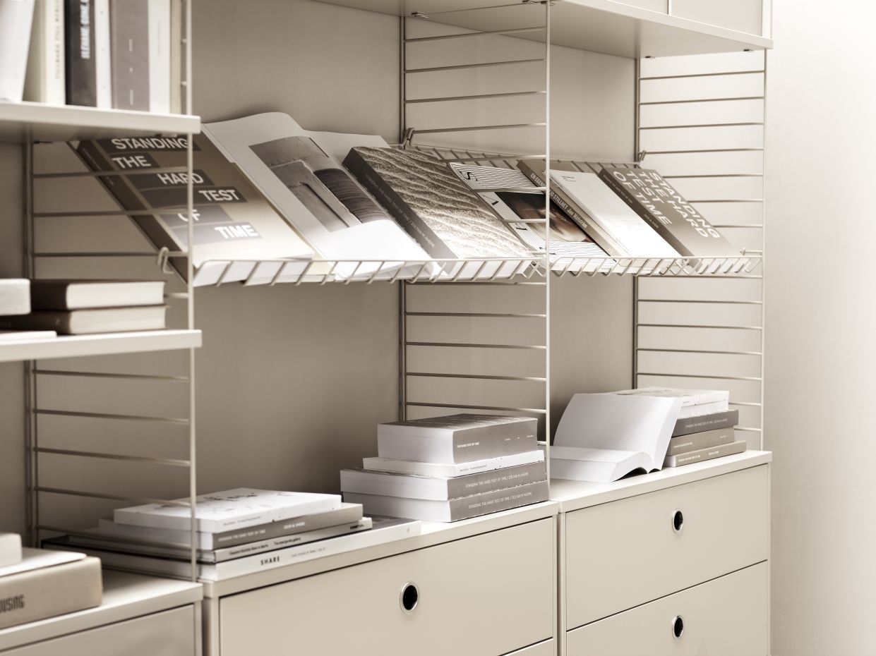 Detailaufnahme: Schwarze String Furniture Zeitschriftenablage aus Metall mit Zeitschriften und Büchern im Regal.