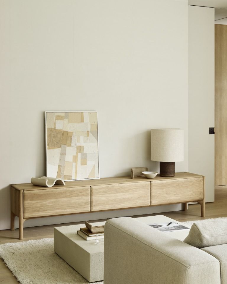 Wohnzimmer mit Ethnicraft TV-Möbel aus Holz, Lampe und Kunstwerk im minimalistischen Stil.