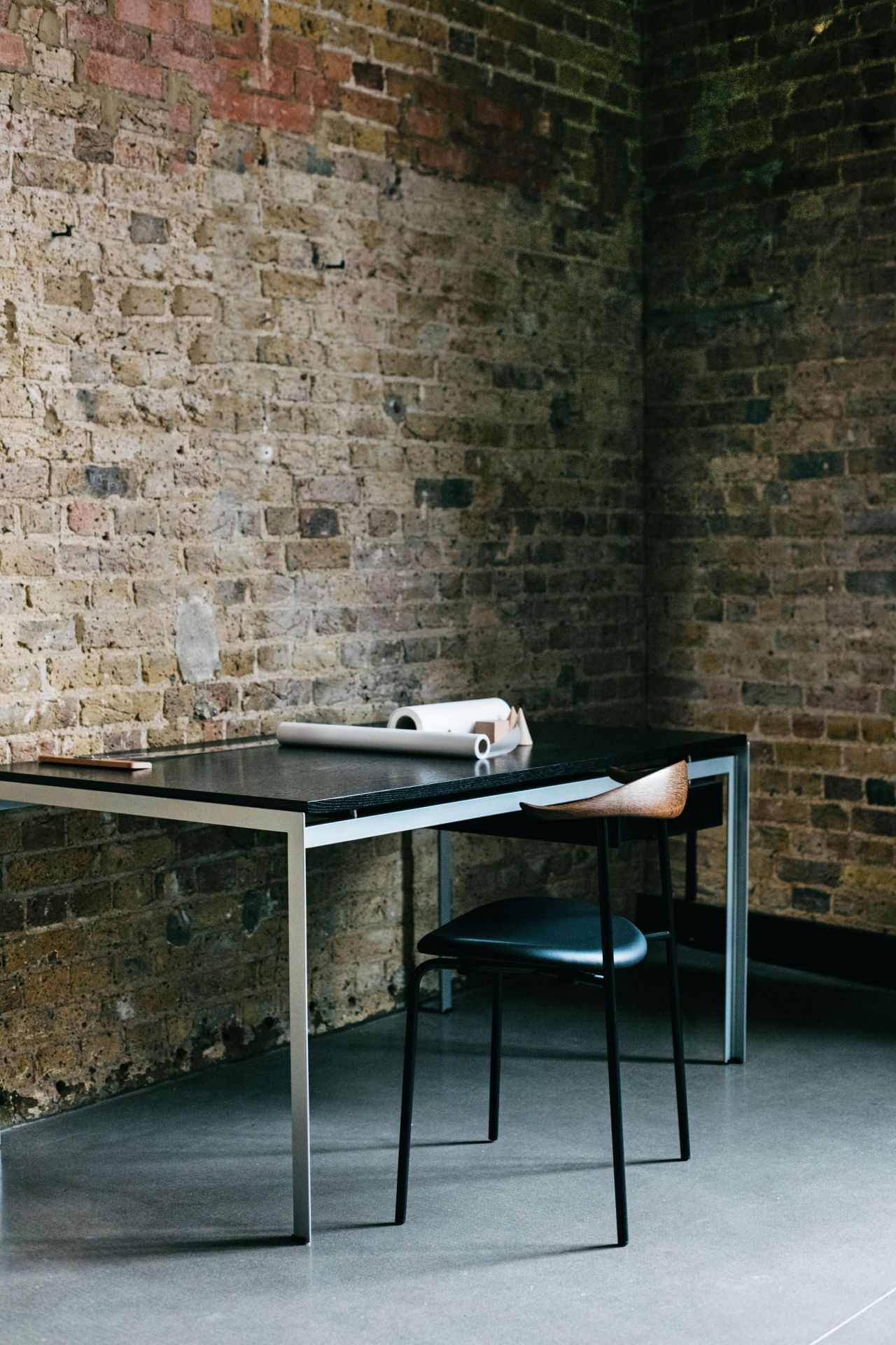 Carl Hansen & Søn PK52A Schreibtisch mit Stuhl vor einer Backsteinwand. Moderner Schreibtisch für Studenten.