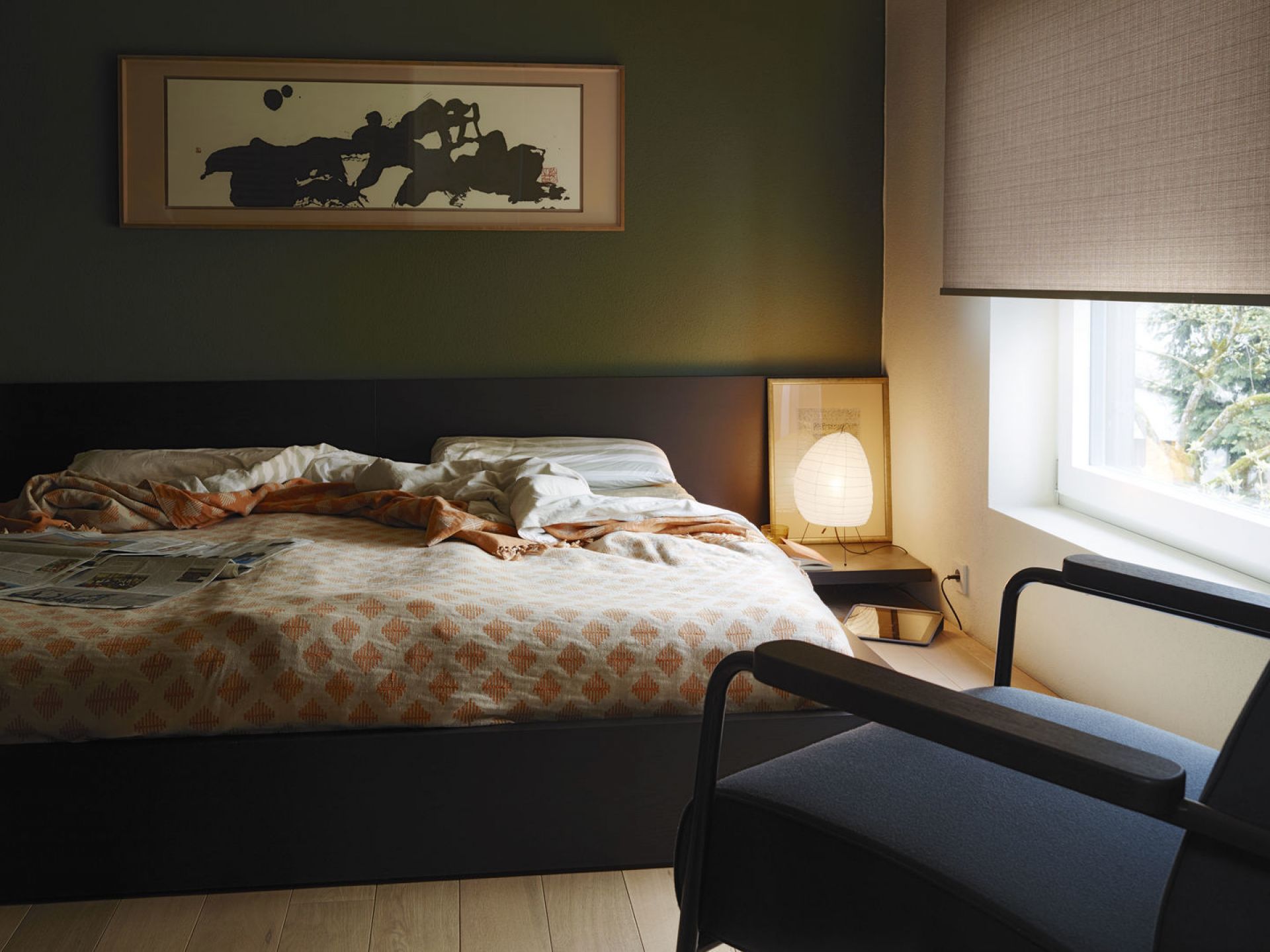 Schlafzimmer mit Bett, Lampe und einem dunklen Fauteuil De Salon Sessel von Vitra im Vordergrund.