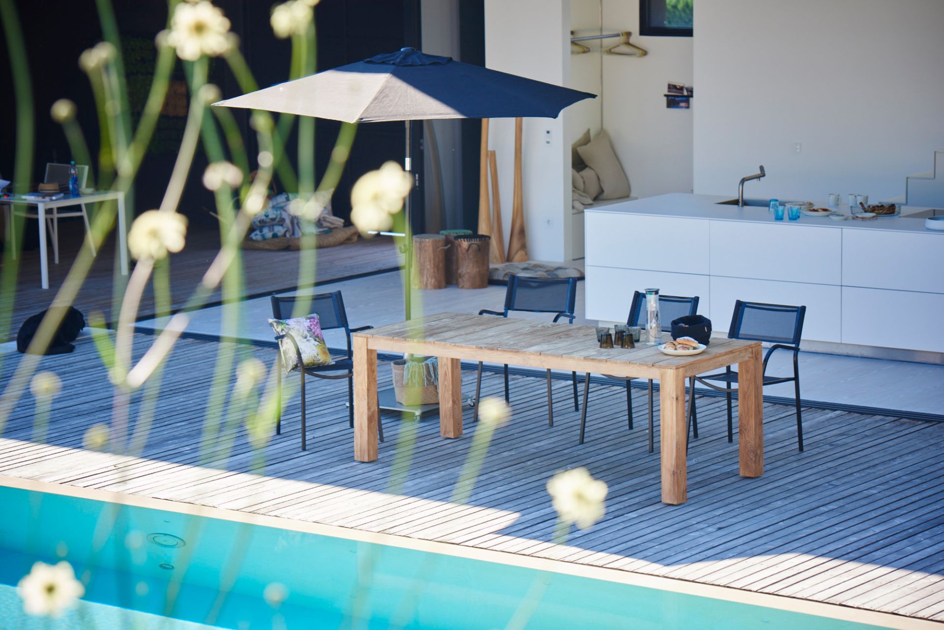 Jan Kurtz Stage Tisch Natur, 220 cm breit, auf Holzterrasse am Pool mit Stühlen.