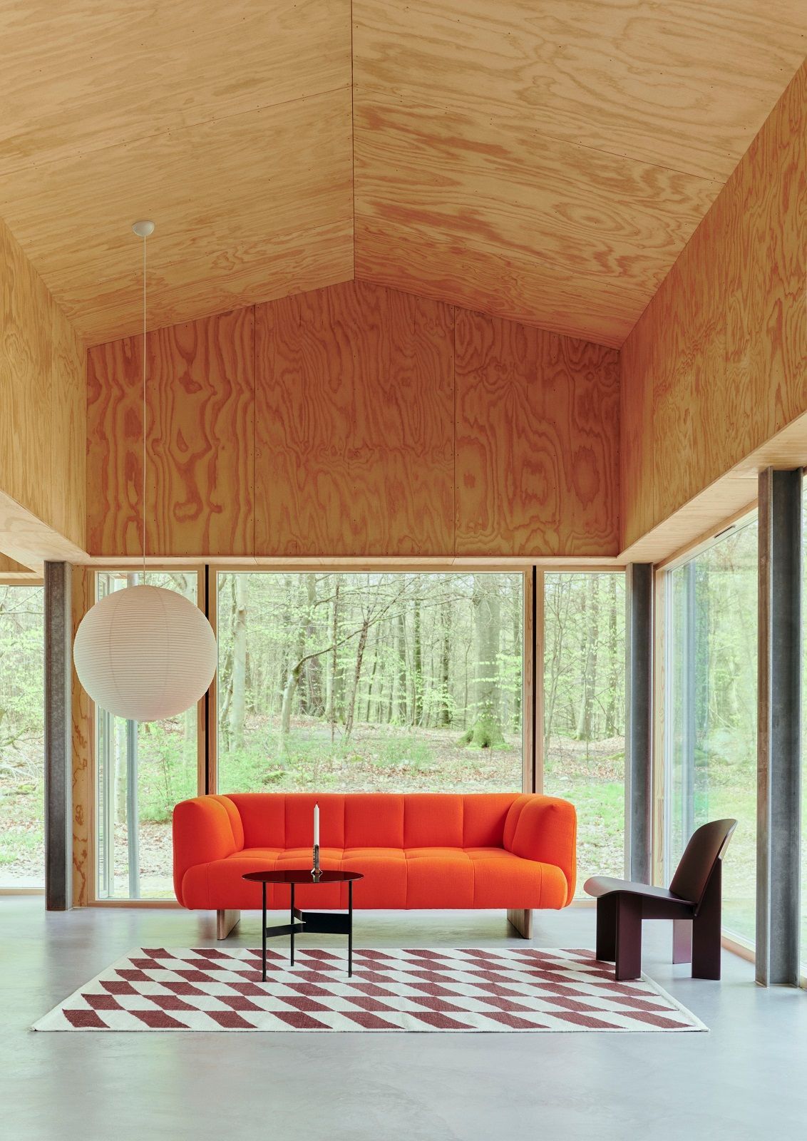 Wohnzimmer mit rotem Sofa und Hay Kelim Teppich mit geometrischem Muster.