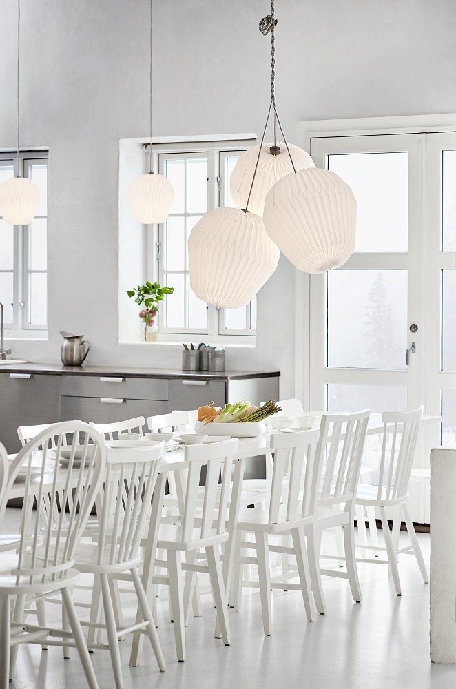 THE BOUQUET Chandelier mit drei Lampenschirmen aus Folie über einem Esstisch in einem hellen Raum.
