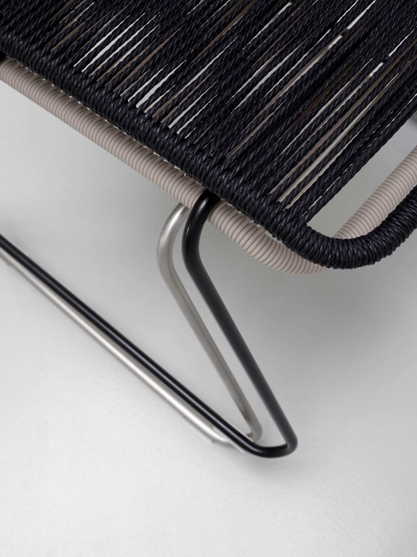 Detailaufnahme: Schwarzer Panton One Stuhl mit geflochtener Sitzfläche und Stahlgestell. Design Stuhl für Esszimmer.