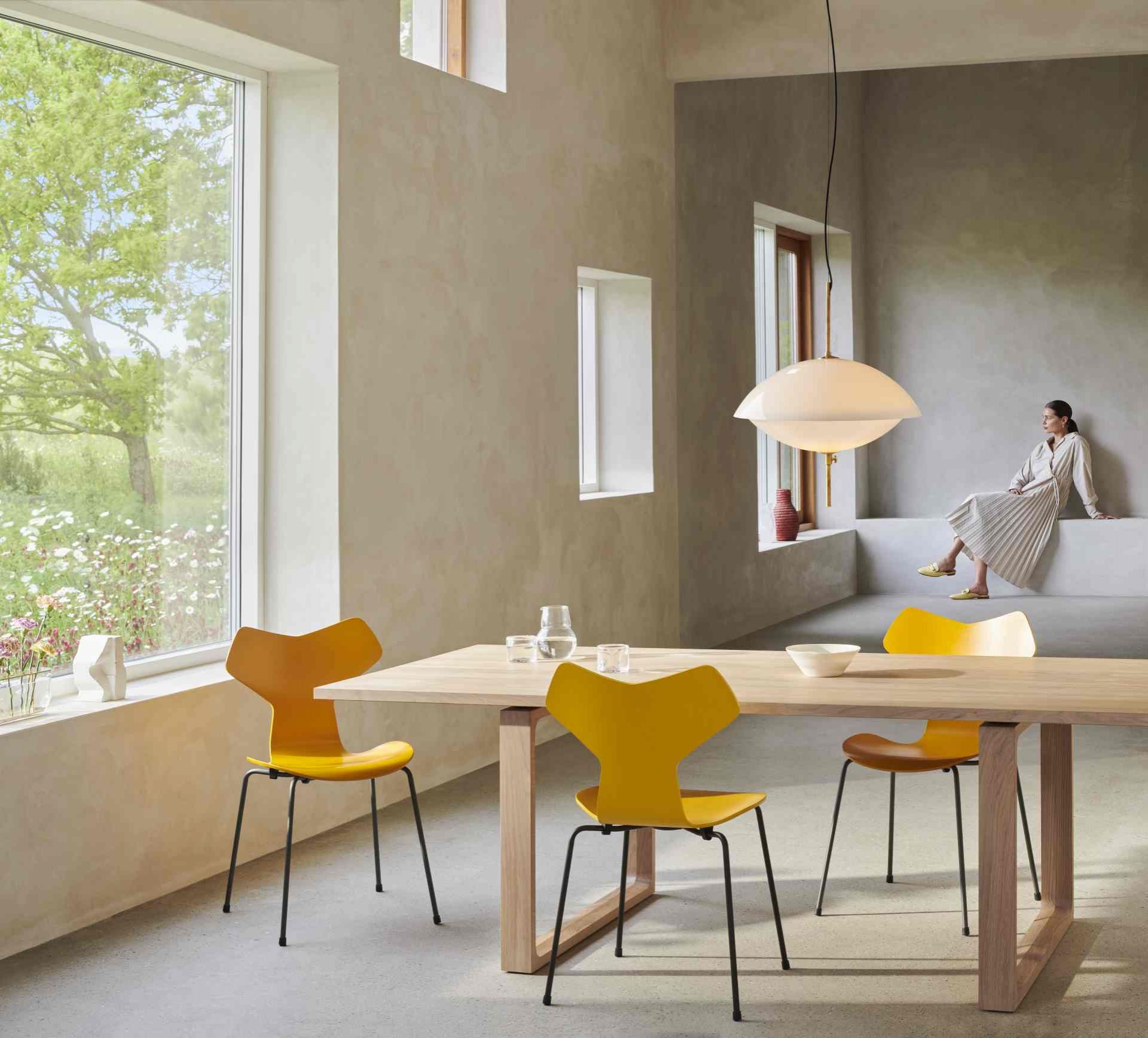 Helle Clam Pendelleuchte von Fritz Hansen über Esstisch mit gelben Stühlen in modernem Raum.