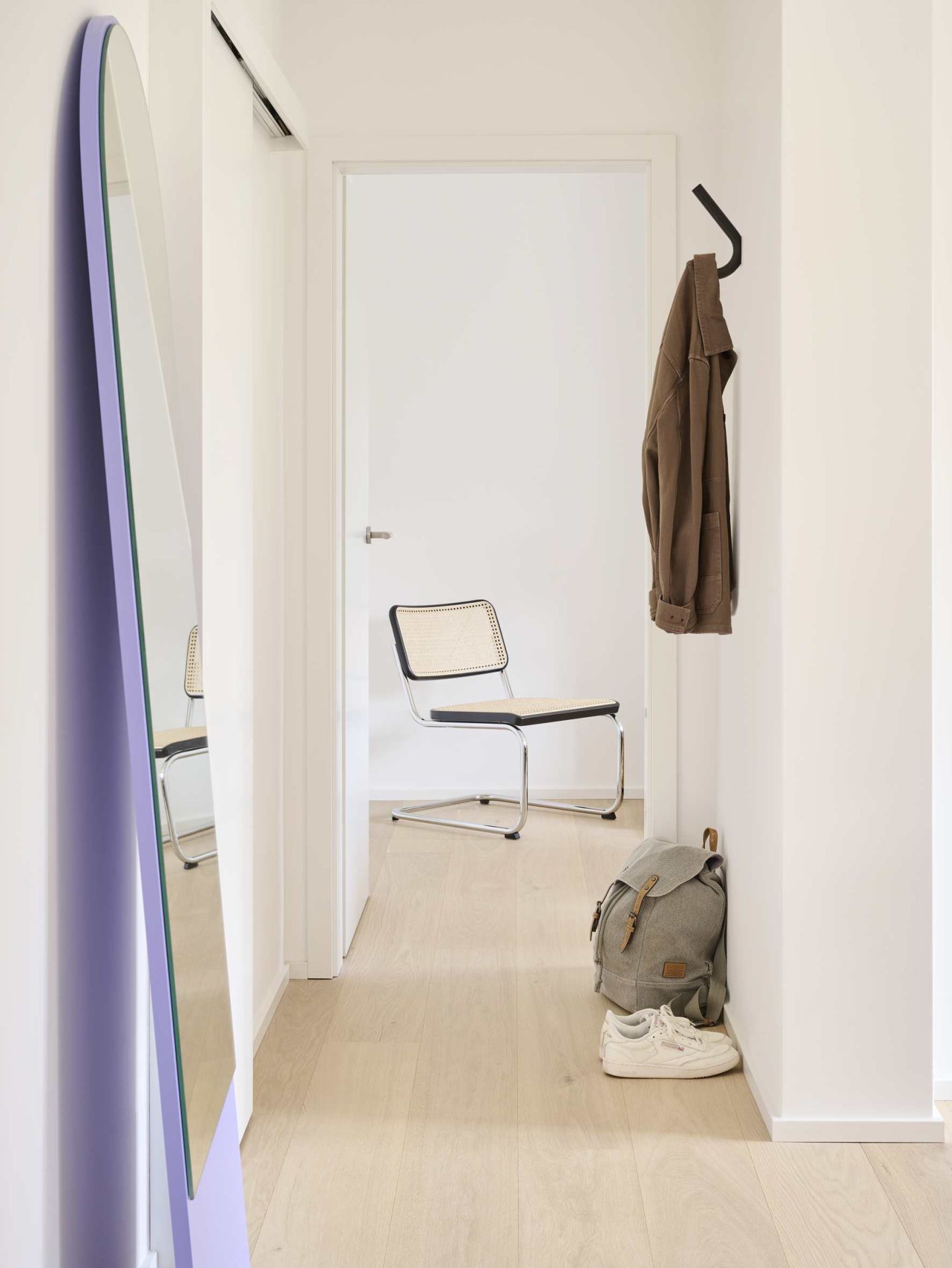 Flur mit Thonet S 12 Wandhaken, Jacke, Rucksack und Schuhen. Minimalistisches Design für Garderobe und Aufbewahrung.