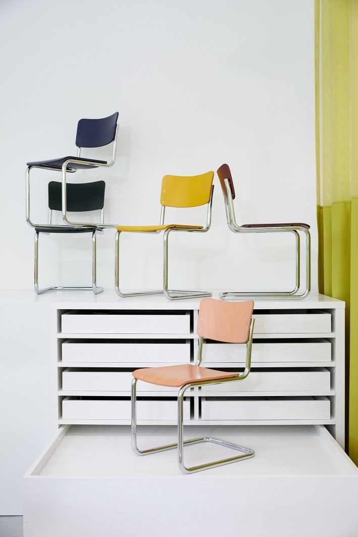 Mehrere Thonet S 43 K Kinderstühle Freischwinger in verschiedenen Farben gestapelt auf weißem Schrank.