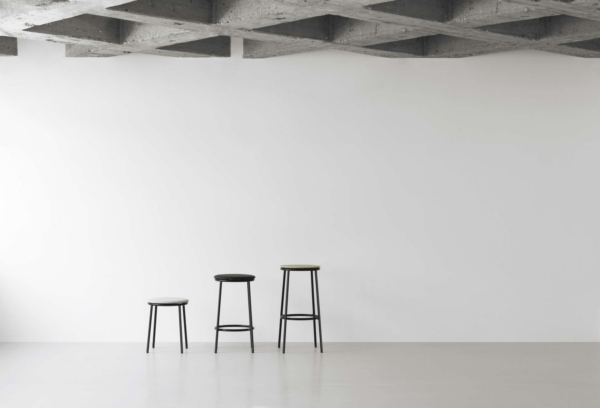 Drei Circa Barstools von Normann Copenhagen in verschiedenen Höhen und Farben vor weißer Wand.