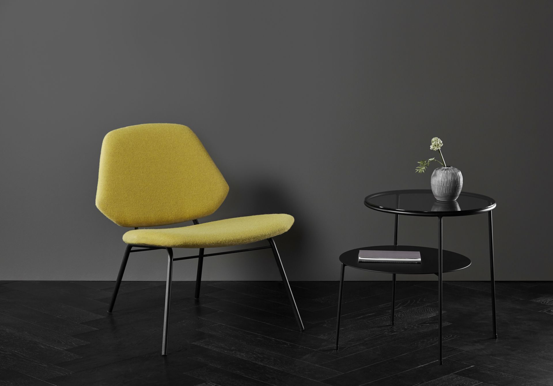 Duo Beistelltisch von Woud, schwarz mit dunklem Rauchglas, neben einem gelben Stuhl.
