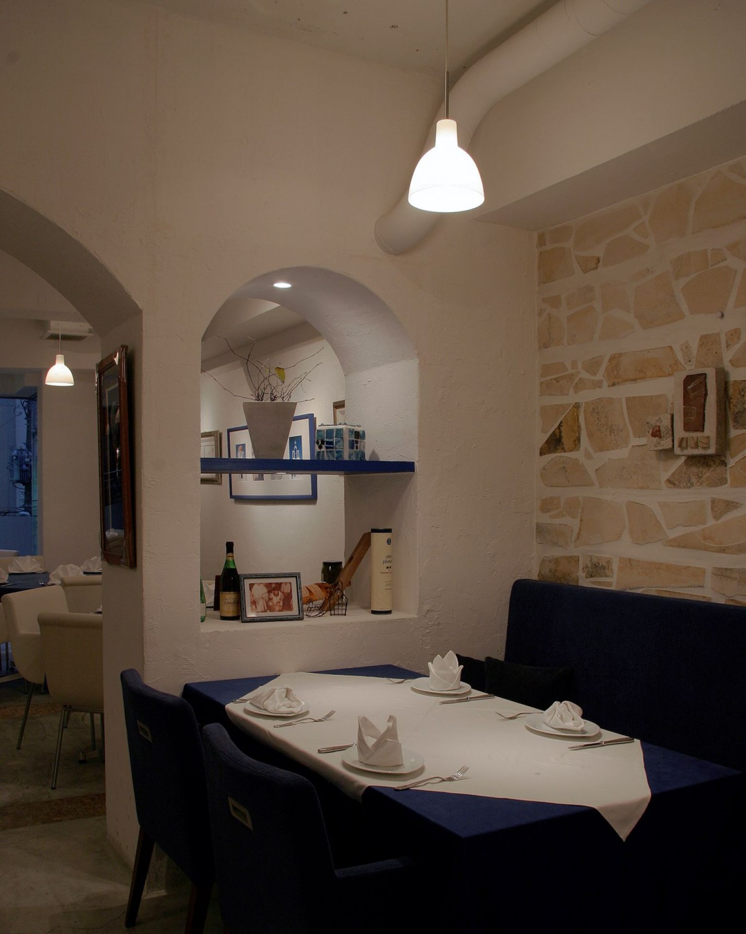 Innenaufnahme eines Restaurants mit einer Toldbod Pendelleuchte von Louis Poulsen über einem gedeckten Tisch.