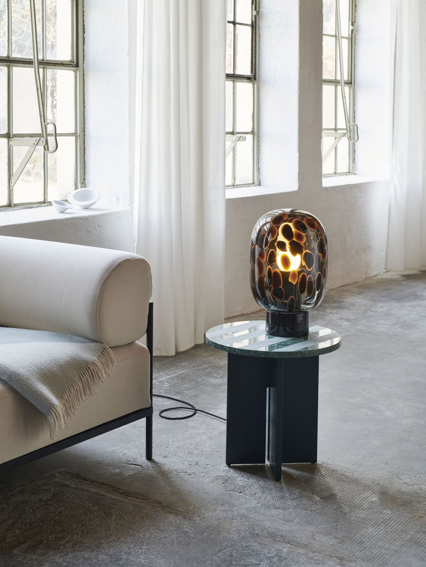 Flakes Tischleuchte Favius in Rauchgrau und Schwarz auf einem Beistelltisch im Interieur.