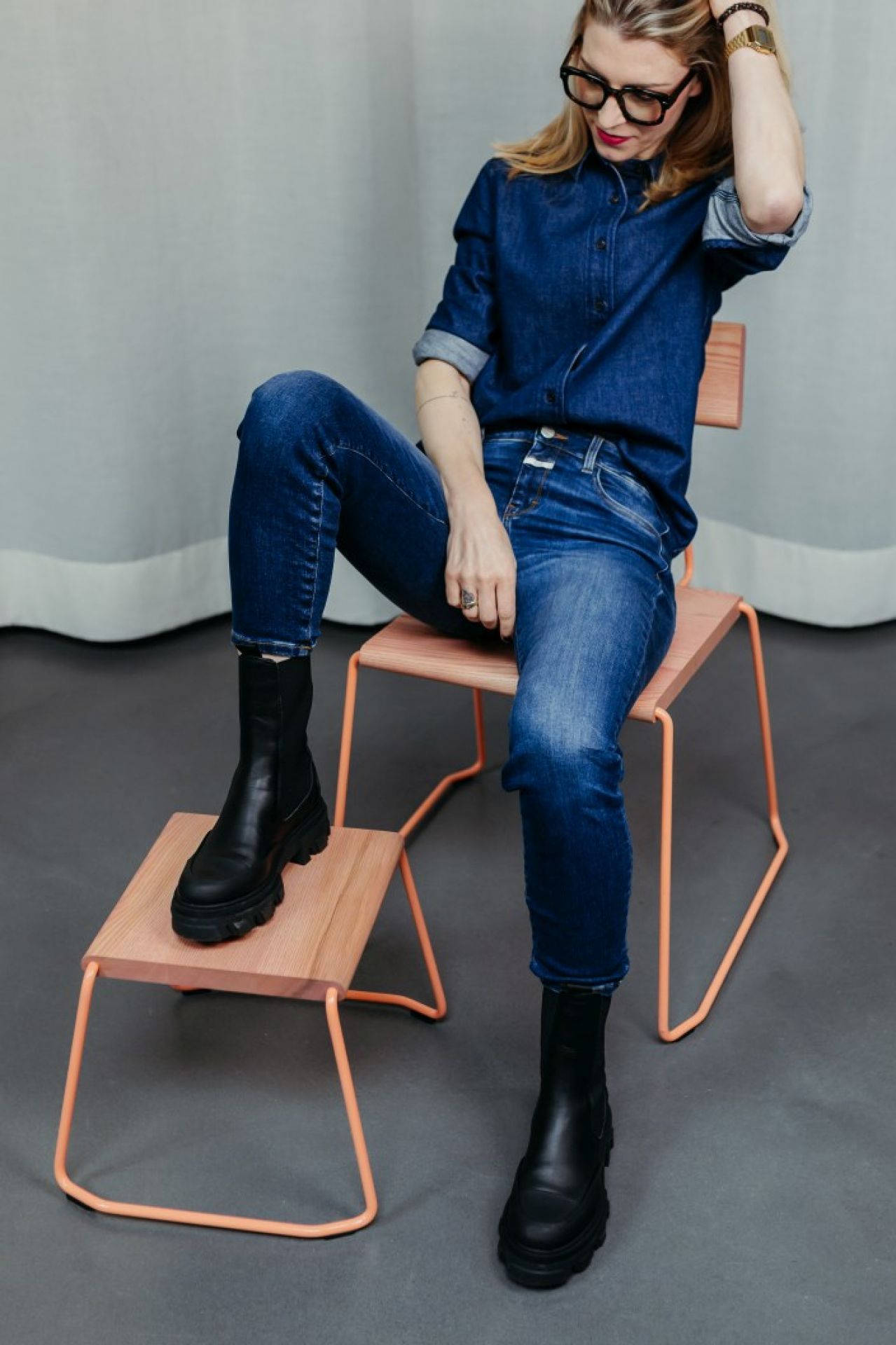 Frau sitzt auf modernem D:005 Stuhl von Fuchs & Habicht. Design-Stuhl mit Holz und Metall.