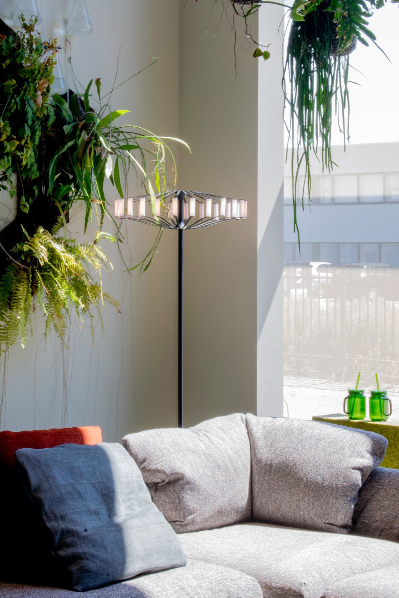 Moderne Wheel Floor Stehleuchte Japth im Wohnzimmer mit grauem Sofa und Pflanzen für gemütliche Atmosphäre.