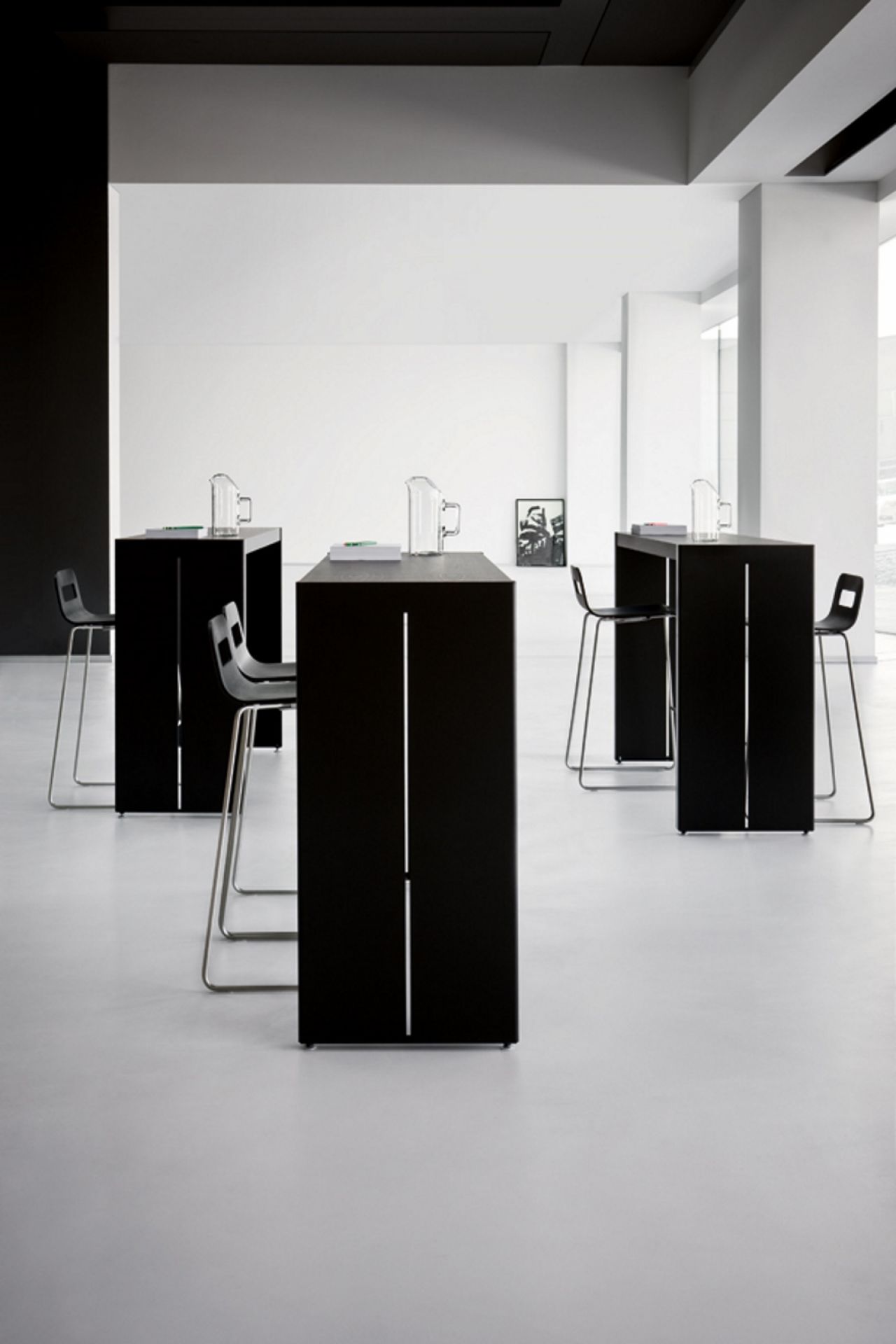 Schwarze Panco Stehtische mit Barhockern in modernem Büro, ideal für Besprechungen und Pausen.