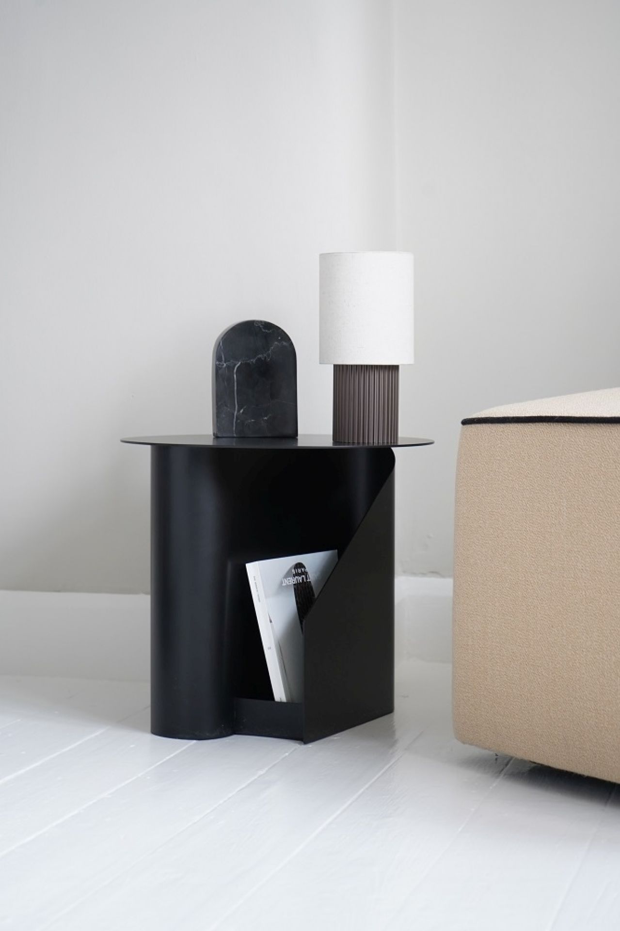 Schwarzer Sentrum Beistelltisch von Woud mit Magazinablage, Lampe und Deko-Objekt auf weißem Holzboden.