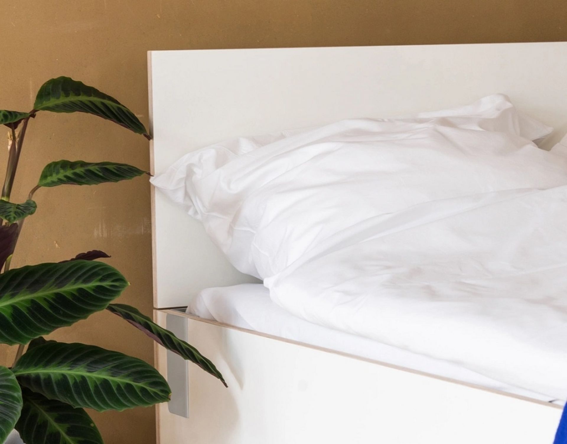 Modernes Kopfteil für Bett von Nils Holger Moormann, elegant und minimalistisch, mit weißen Bettwaren.