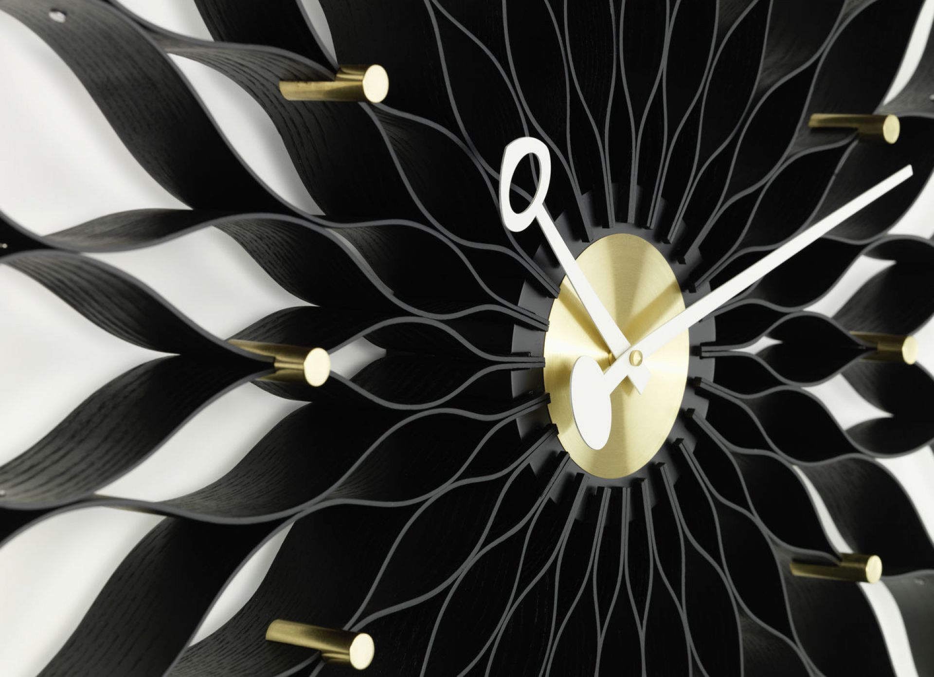 Detailaufnahme der Vitra Sunflower Clock Wanduhr in Esche schwarz mit Messing-Akzenten.