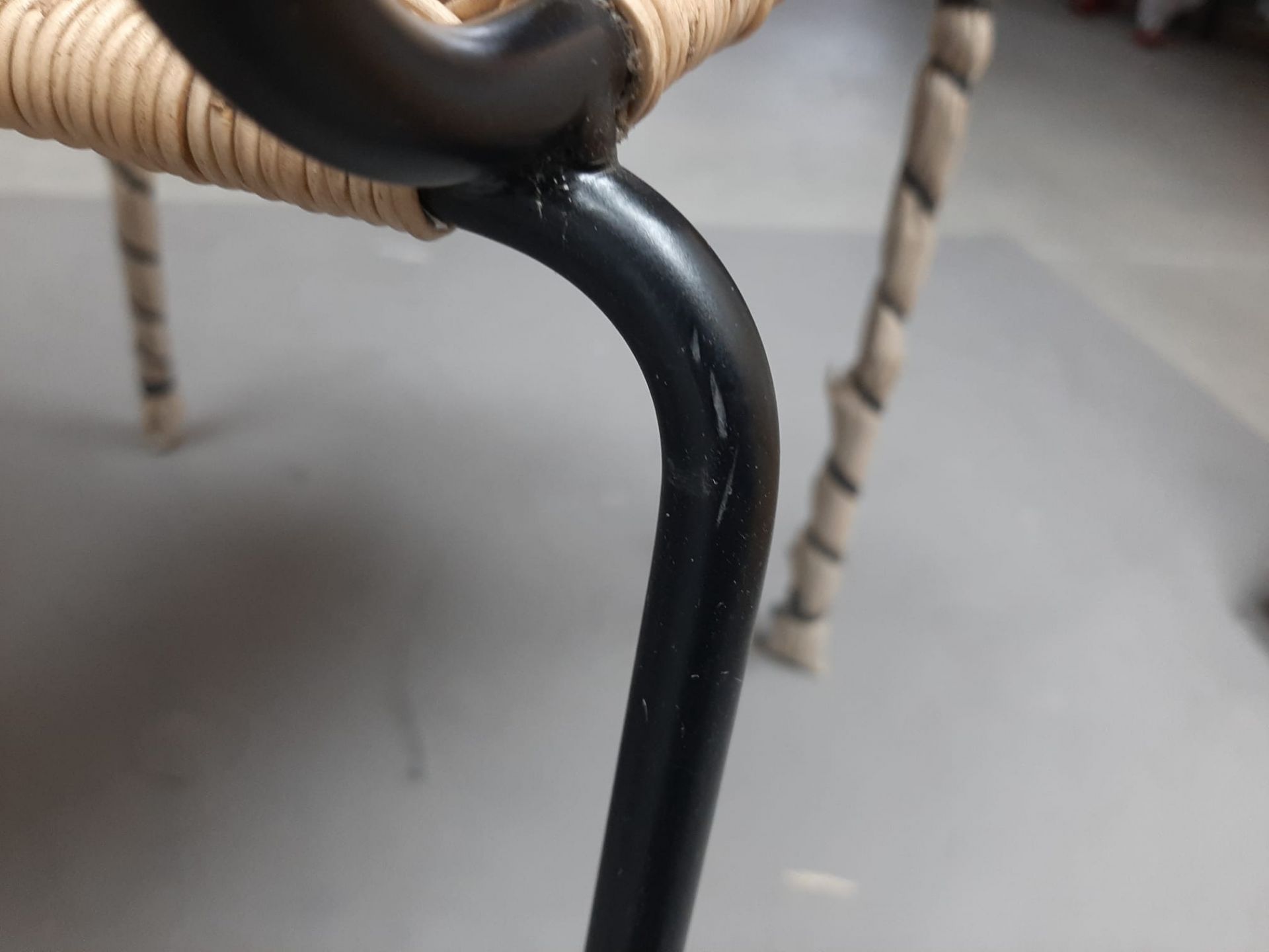 Detailaufnahme vom Stuhl TT 54 (Mängelexemplar): Schwarzes Metallgestell mit Gebrauchsspuren und Rattan-Sitzfläche. Designstuhl für Wohnzimmer und Esszimmer.