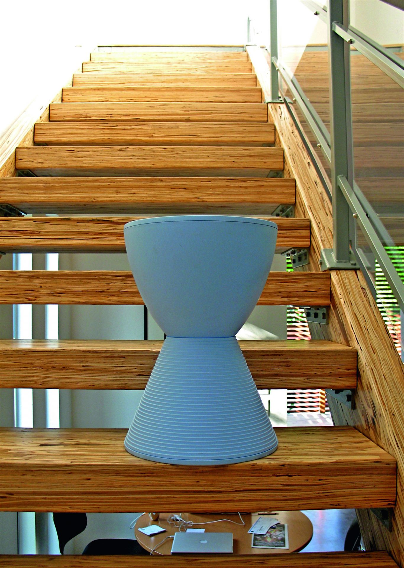 Taubengrauer Prince AHA Hocker von Kartell auf einer Holztreppe, modernes Designmöbel.