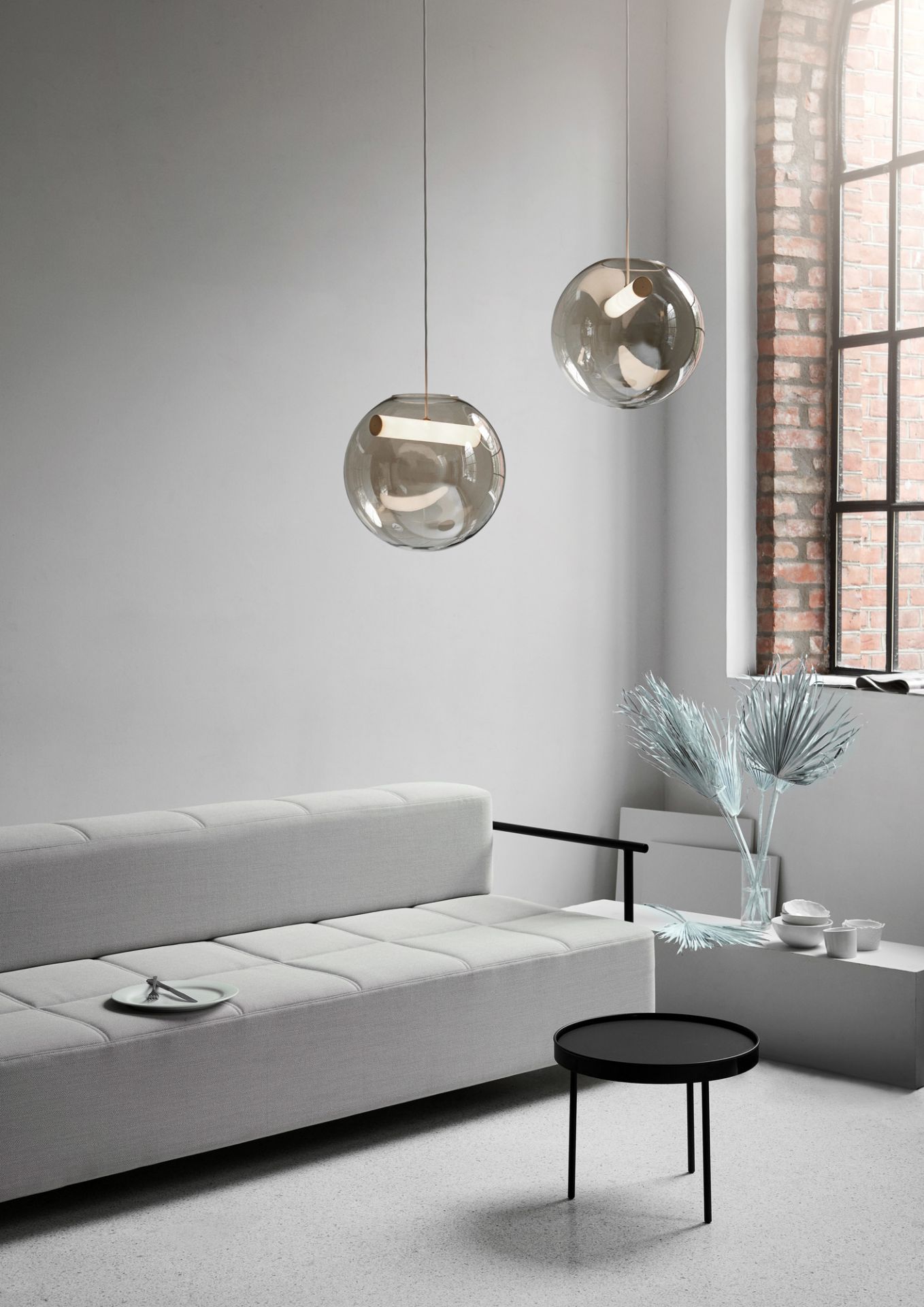 Zwei Northern Reveal Pendelleuchten aus Glas über einem modernen Wohnzimmer mit Sofa.