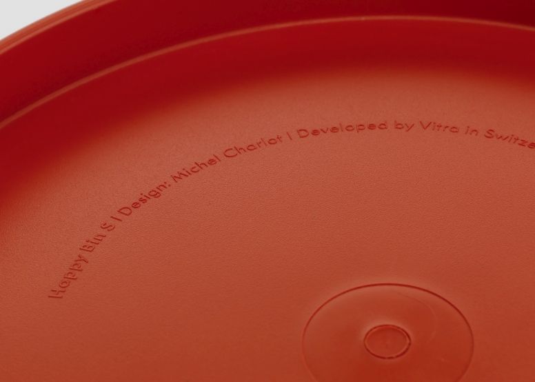 Detailaufnahme des roten Vitra Happy Bin Papierkorbs mit eingeprägtem Designhinweis.