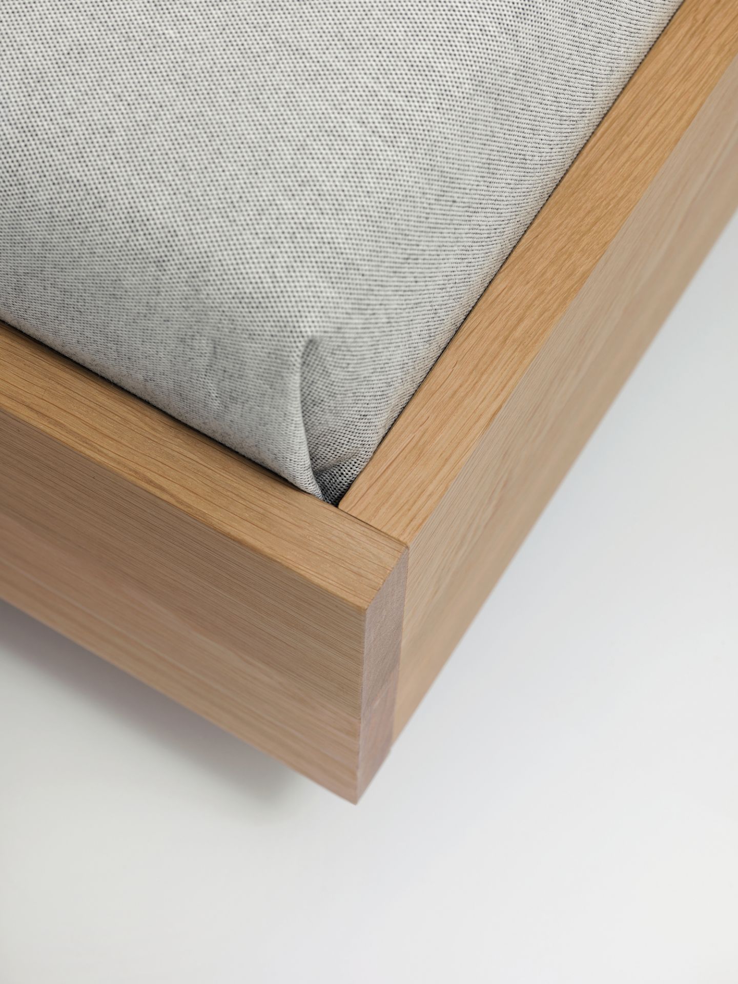 Detailaufnahme vom Simple HI Holzbett mit hellem Holzrahmen und grauem Stoffbezug.