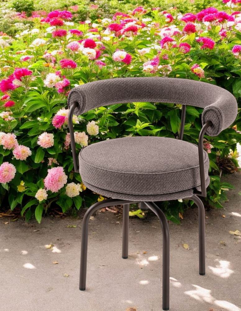 Grauer Cassina Drehsessel "7 Fauteuil Tournant" für den Outdoor-Bereich vor einem Blumenbeet.