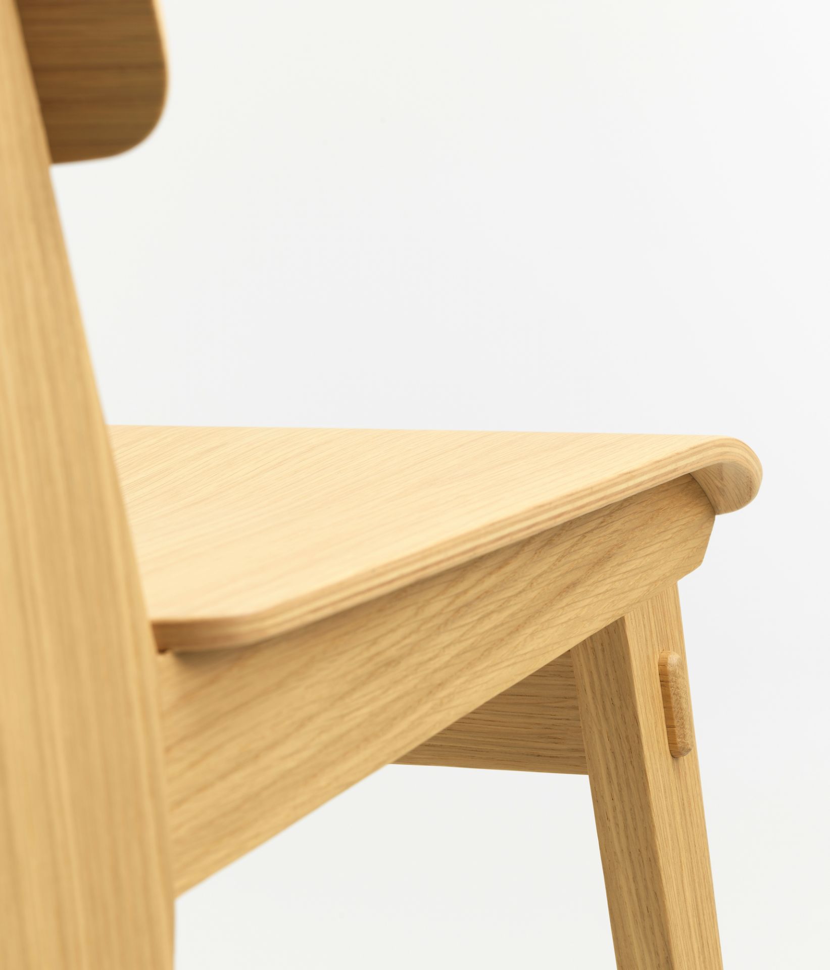 Detailaufnahme des Vitra Chaise Tout Bois Stuhls: Sitzfläche und Bein aus hellem Holz.