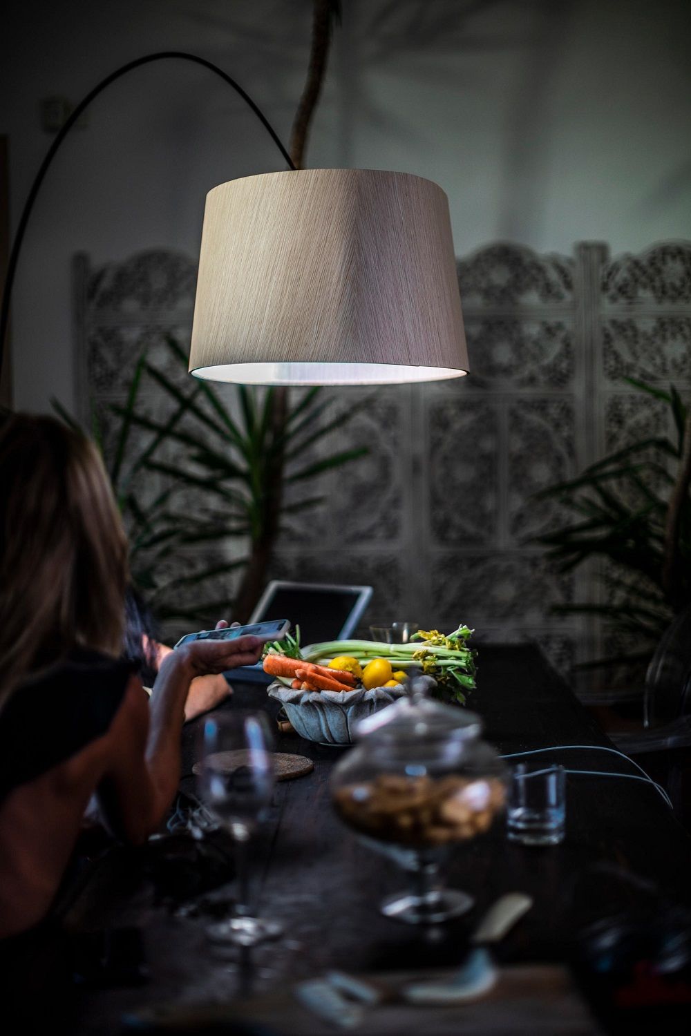 Graue Twiggy Stehleuchte von Foscarini über Esstisch mit Gemüse und Person im Hintergrund.