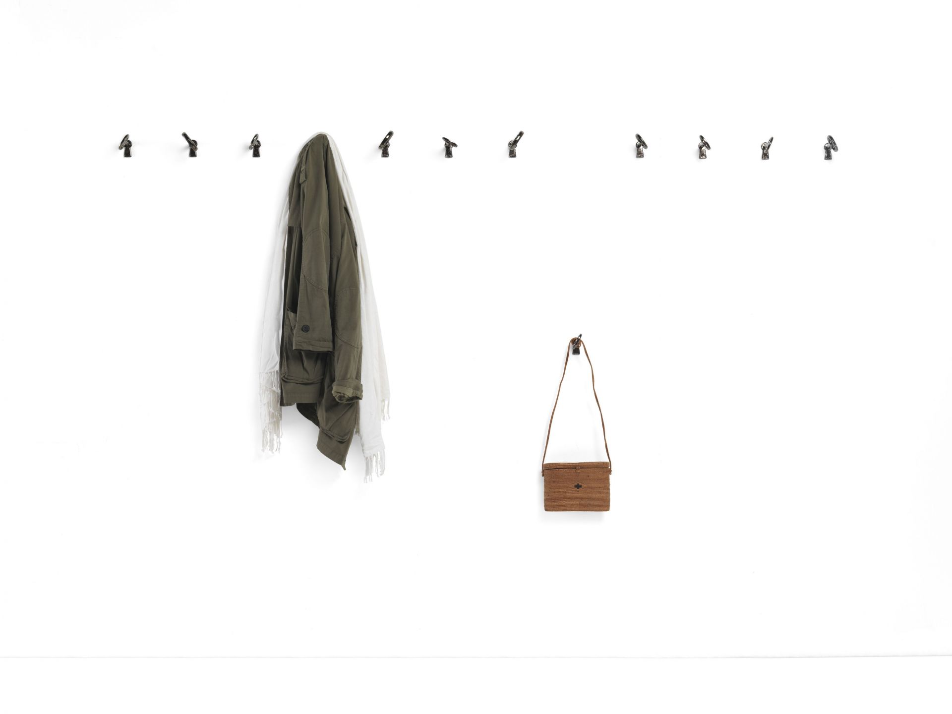 Memorie Wandhaken von Mogg, 4er Set: Wandgarderobe mit Jacke und Tasche an weißer Wand.
