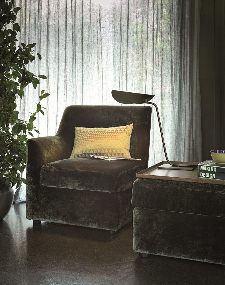 Nahaufnahme der Oluce Plume Tischleuchte auf einem Beistelltisch neben einem Sessel.