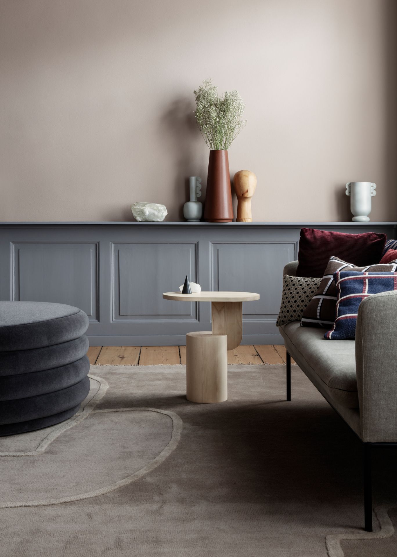 Ferm Living Insert Beistelltisch aus Holz im Wohnzimmer neben Sofa und Pouf.