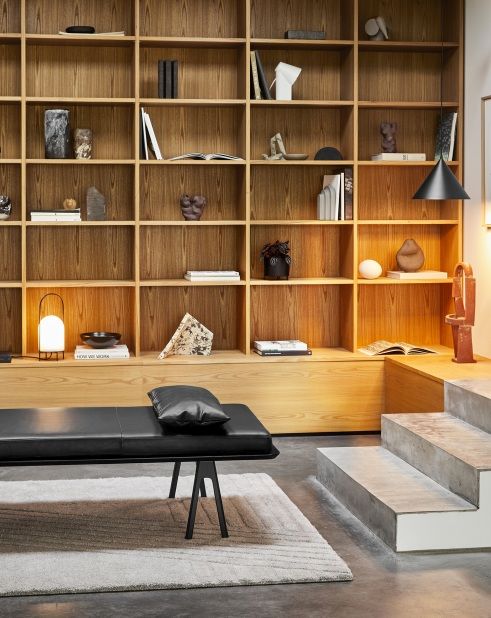 Grauer Kyoto Rug Teppich von Woud (80x200 cm) im modernen Wohnzimmer mit Bank und Regal.