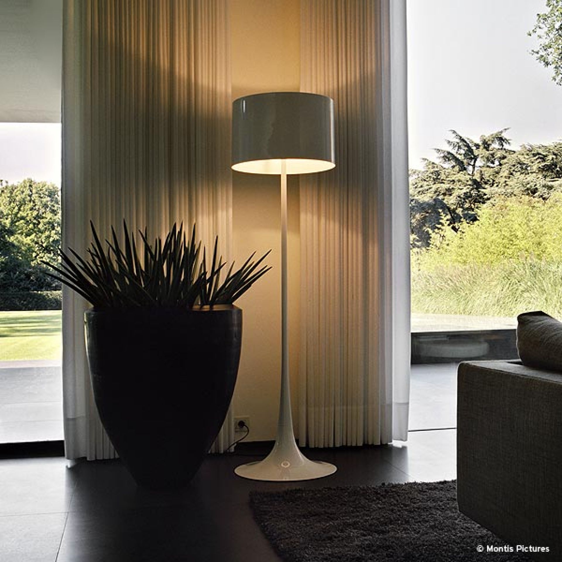 Weiße Flos Stehleuchte "Spun Light F" im modernen Wohnzimmer mit Pflanze und Fenster.