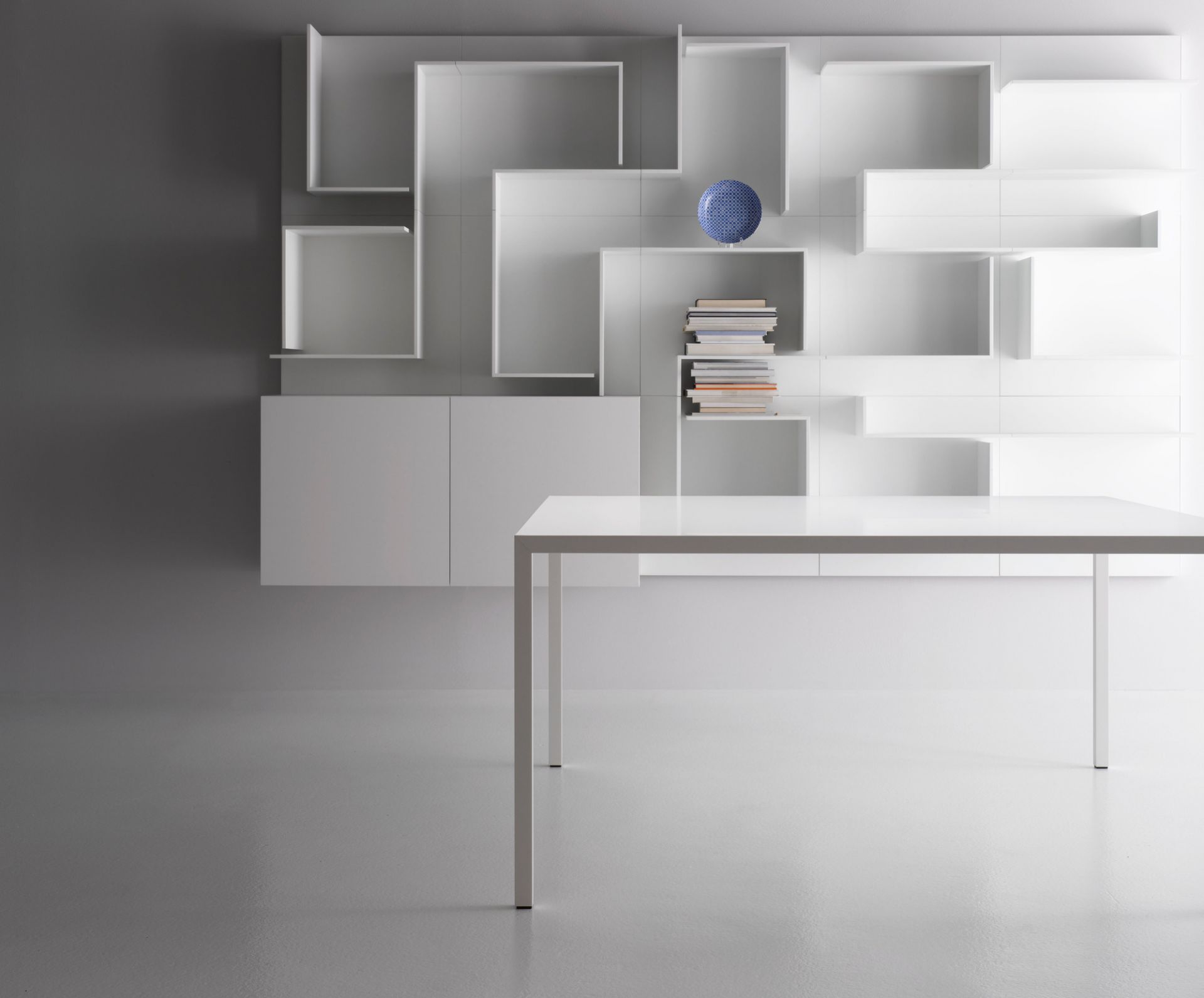 Weißer Tense Tisch von MDF Italia mit passendem weißen Wandregal und Bücher im Hintergrund.