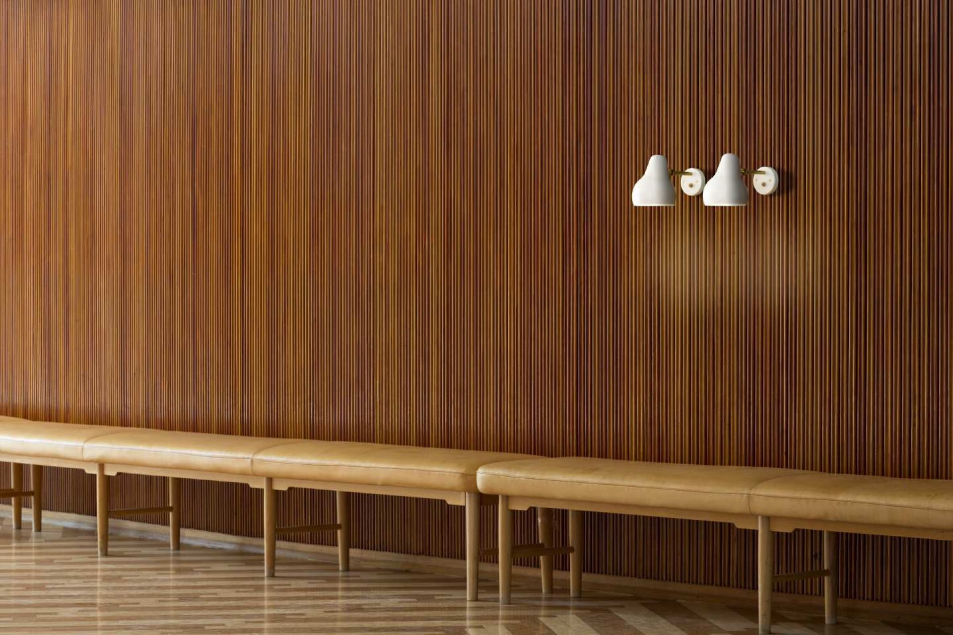 Zwei weiße VL38 Wandleuchten von Louis Poulsen an einer braunen Holzvertäfelung über einer hellen Sitzbank.