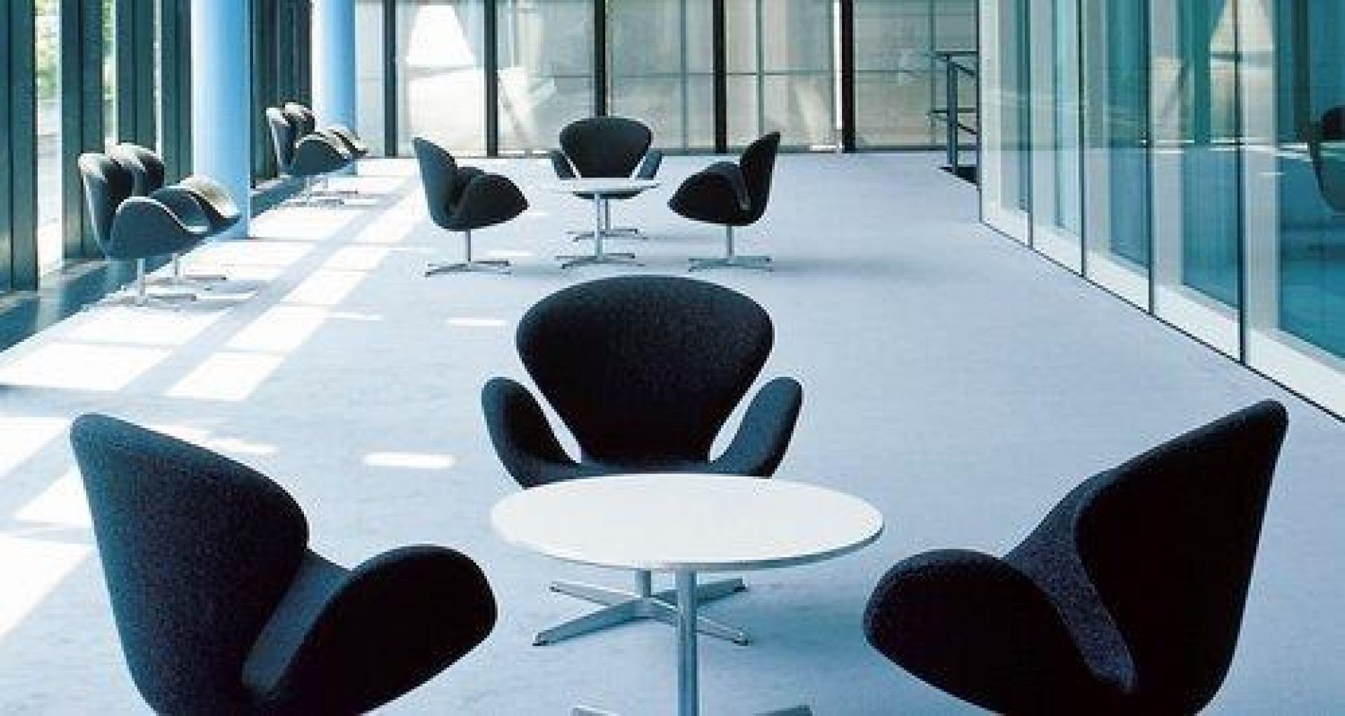 Innenaufnahme mit mehreren Fritz Hansen Tischen und Sesseln in einem modernen Büro.