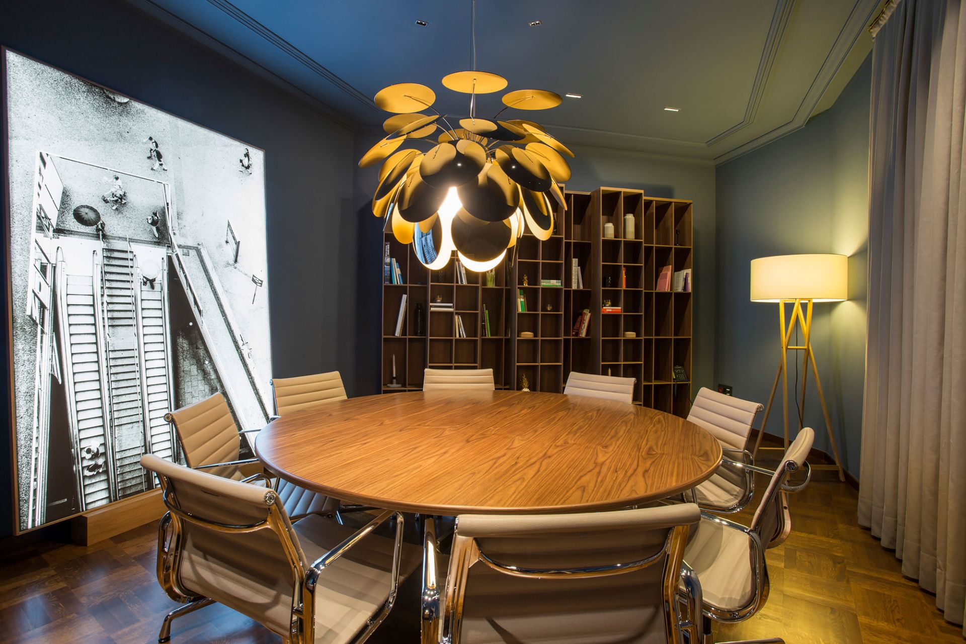 Discocó 88 Pendelleuchte in Schwarz und Gold über einem runden Tisch in einem Besprechungsraum.