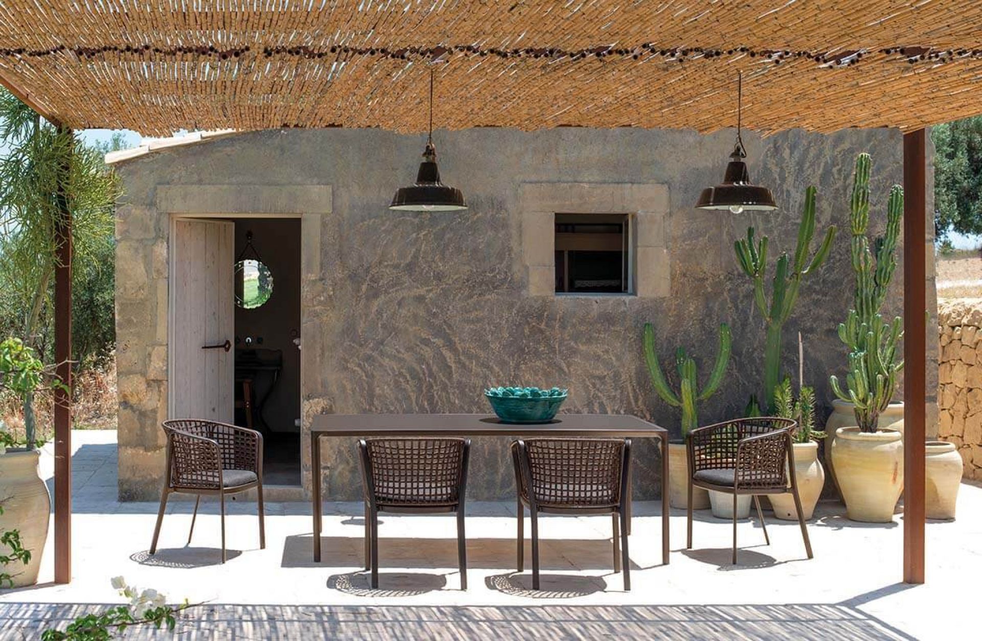 Carousel Armlehnstuhl von Emu: Outdoor-Stuhl mit Armlehnen und passendem Esstisch auf einer Terrasse.