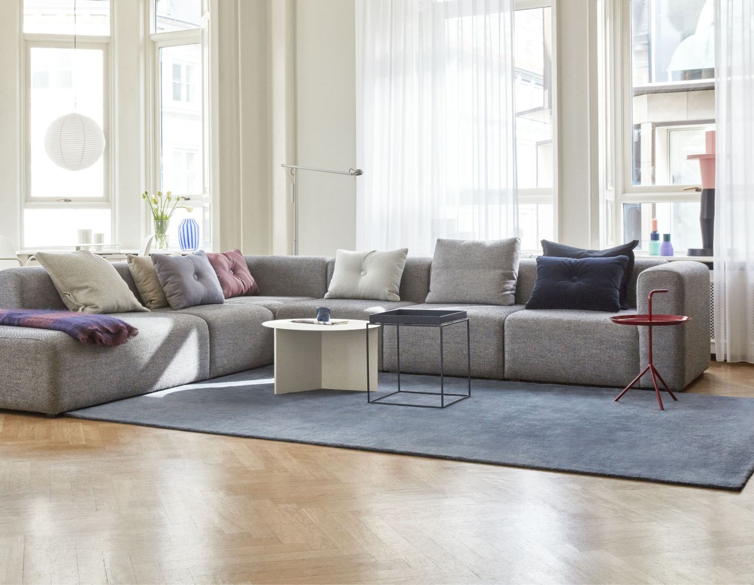 Wohnzimmer-Szene mit Hay Slit Table Rund Beistelltisch in Weiß neben einem grauen modularen Sofa.