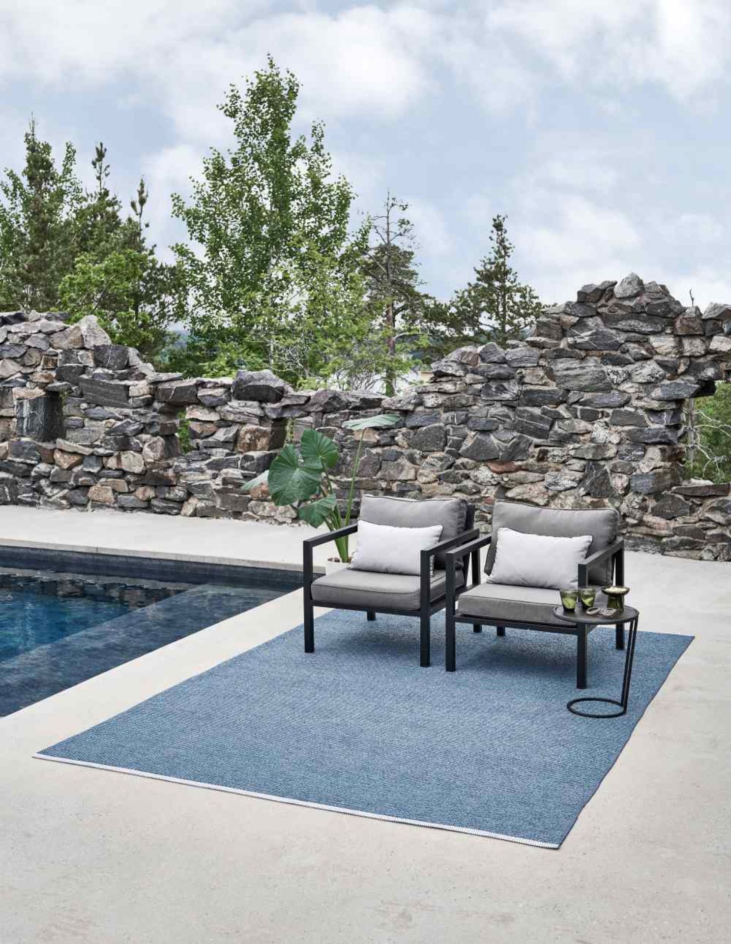 Dunkelroter Pappelina Mono Kunststoffteppich 230x320 cm im Außenbereich mit Gartenmöbeln. Robuster, wetterfester Teppich.