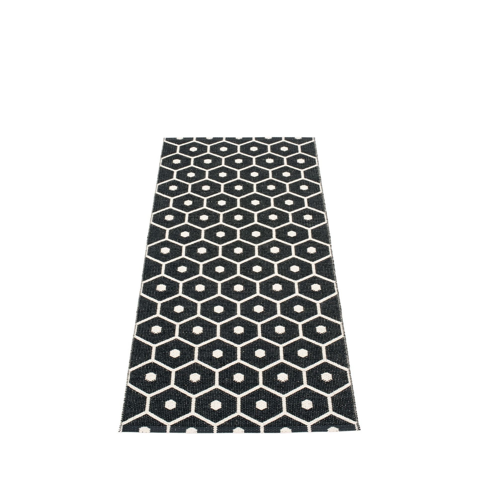 Pappelina Honey Kunststoffteppich 70x160 cm mit schwarzem Sechseckmuster und weißen Punkten. Moderner Teppich für Innen und Außen.