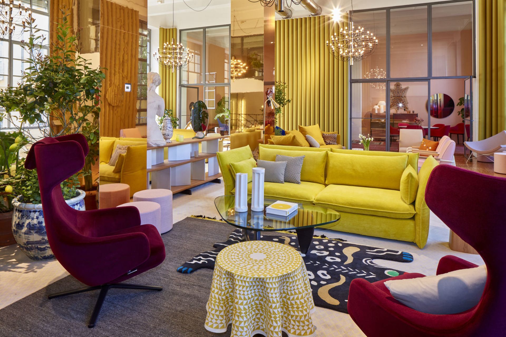 Innenaufnahme mit zwei burgunderroten Grand Repos Sesseln von Vitra in einem farbenfrohen Wohnzimmer.