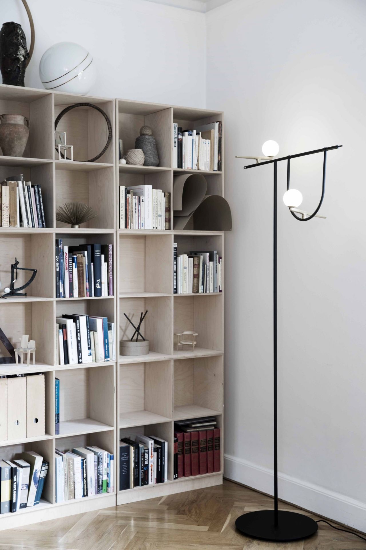 Schwarze Yanzi Stehleuchte von Artemide mit zwei leuchtenden Kugeln im modernen Wohnzimmer neben Bücherregal.