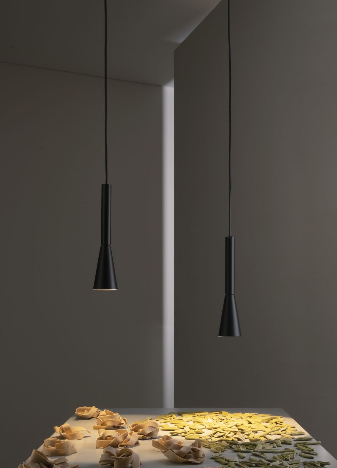 Zwei schwarze Colibrì Pendelleuchten von Martinelli Luce über einem Tisch mit Pasta.