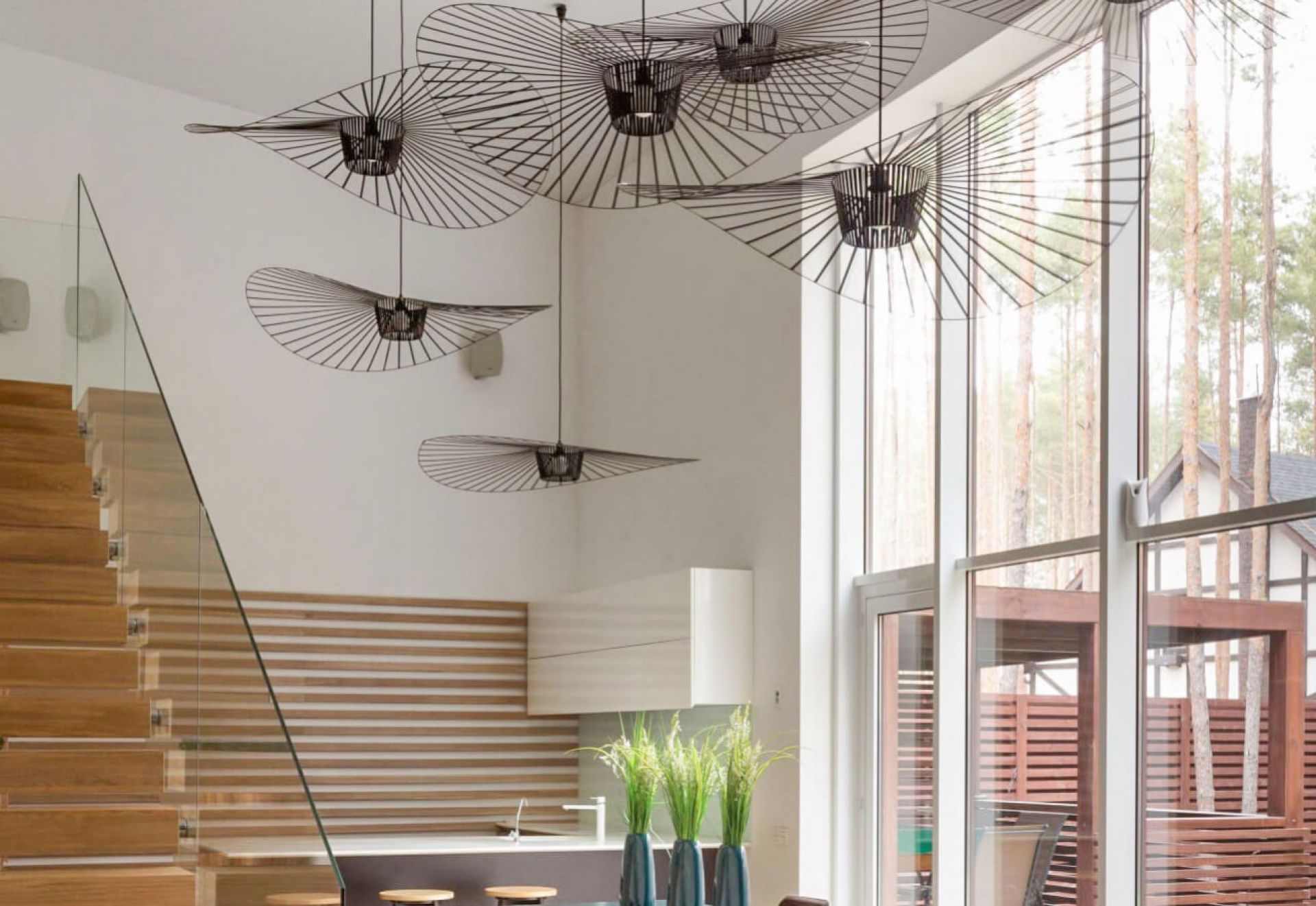 Mehrere Vertigo Pendelleuchten von Petite Friture in einem modern eingerichteten Wohnraum mit Treppe und Fenster.