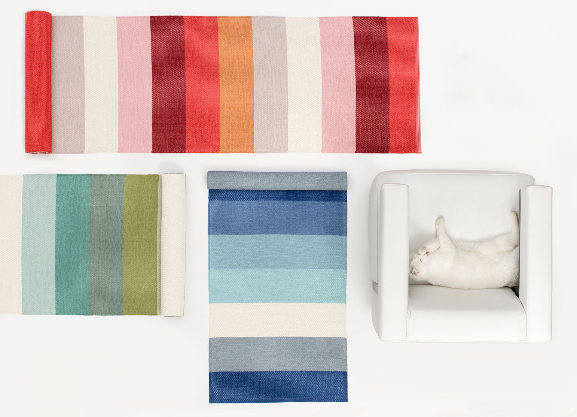 Molly Kunststoffteppich von Pappelina, verschiedene Farben und ein weißer Sessel mit Katze.